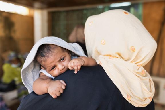 An infant held over a woman's shoulder